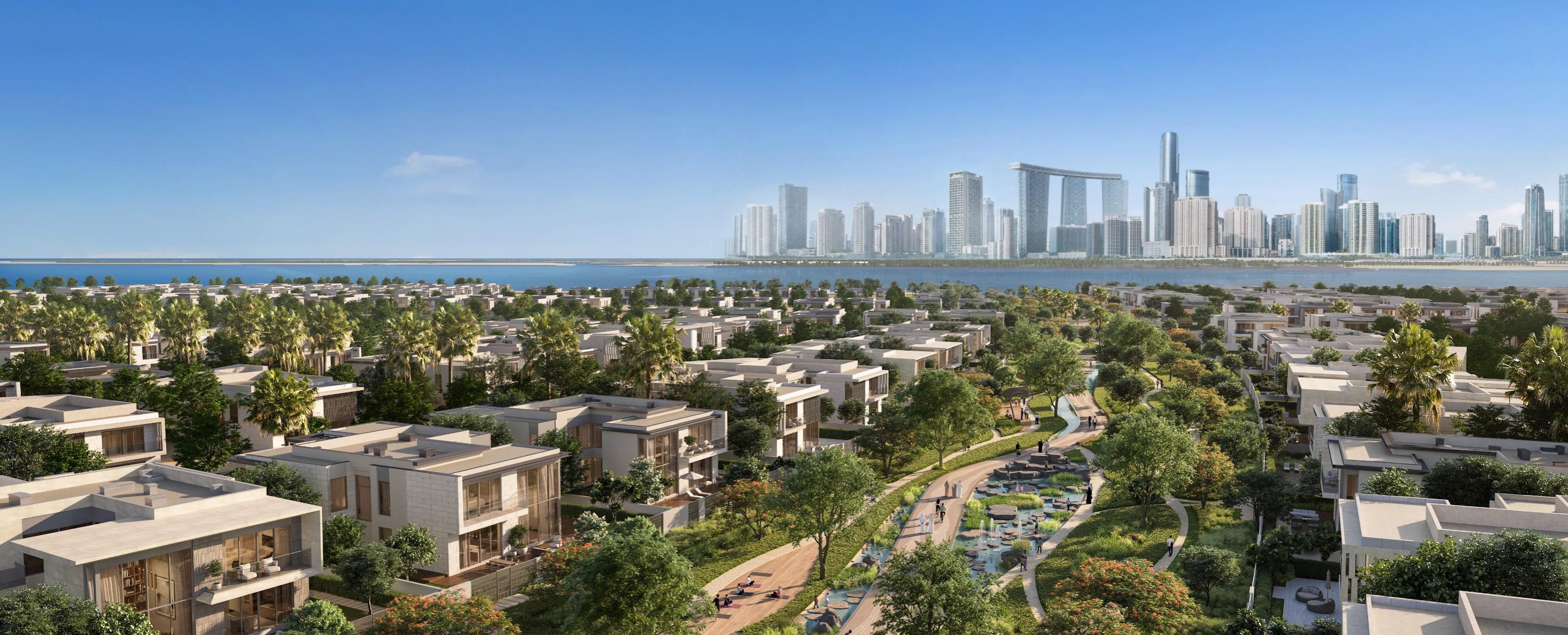 Aerial of low-rise villas along a green landscaped spine at Marsa Al Saadiyat, skyline in the distance